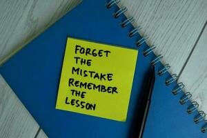 Forget The Mistake Remember The Lesson write on sticky notes isolated on office desk. photo