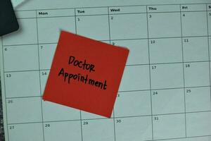 monthly Calendar and Doctor Appointment write on sticky notes isolated on the table photo