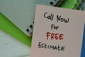 Call Now For Free Estimate write on sticky note isolated on Wooden Table. photo
