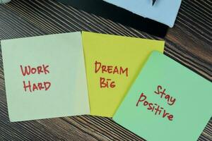 Concept of Work Hard, Dream Big, Stay Positive write on sticky notes isolated on Wooden Table. photo