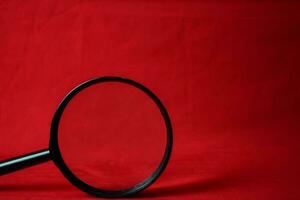 Magnifying glass on red background photo