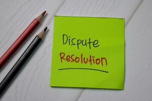 Dispute Resolution write on sticky note with magnifying glass isolated on wooden table. photo