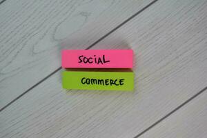 Social Commerce write on sticky notes isolated on Wooden Table. photo