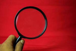 Magnifying glass on red background photo