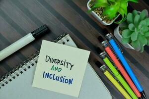 Diversity and Inclusion write on sticky notes isolated on Wooden Table. photo