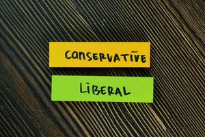 Conservative and Liberal write on sticky notes isolated on Wooden Table. photo