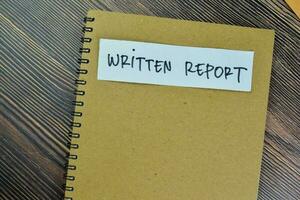 Concept of Written Report write on a book isolated on Wooden Table. photo