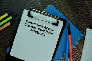 Consisten Action Creates Consistent Results text on the Book isolated on office desk background photo