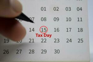 Tax Day on monthly Calendar and marked 15th isolated on office desk photo