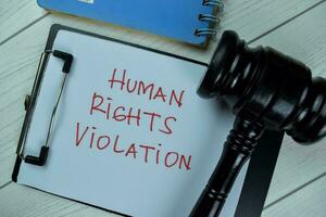 Concept of Human Rights Violation write on a paperwork with gavel isolated on Wooden Table. photo