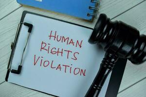 Concept of Human Rights Violation write on a paperwork with gavel isolated on Wooden Table. photo