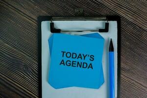 Today's Agenda write on sticky notes isolated on Wooden Table. photo