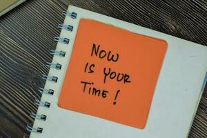 Concept of Now Is Your Time write on sticky notes isolated on Wooden Table. photo