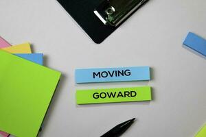 Moving Goward text on sticky notes with office desk concept photo