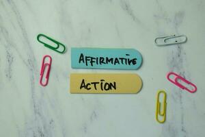 Affirmative Action write on sticky notes isolated on office desk. photo