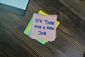Concept of It's Time For A New Job write on sticky notes isolated on Wooden Table. photo