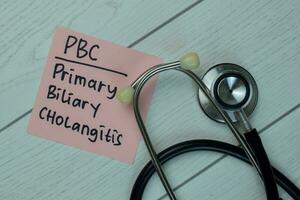 PBC - Primary Biliary Cholangitis write on sticky notes isolated on Wooden Table. Medical concept photo