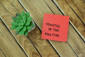 Concept of Minutes of The Meeting write on sticky notes isolated on Wooden Table. photo