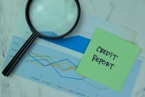 Concept of Credit Report write on sticky notes with diagram or graph isolated on Wooden Table. photo