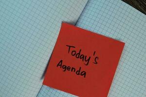 Today's Agenda write on sticky notes isolated on Wooden Table. Business concept photo