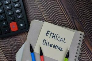 Ethical Dilemma write on sticky notes isolated on Wooden Table. photo