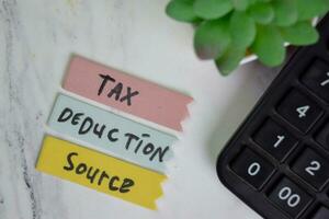 Tax Deduction Source write on sticky notes isolated on Wooden Table. photo