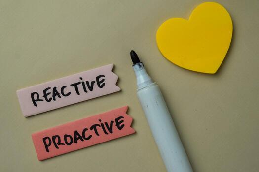Reactive and Proactive write on sticky notes isolated on office desk. photo
