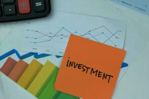 Concept of Investment write on sticky notes with diagram or graph isolated on Wooden Table. photo