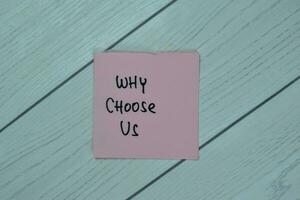 Concept of Why Choose Us write on sticky notes isolated on Wooden Table. photo