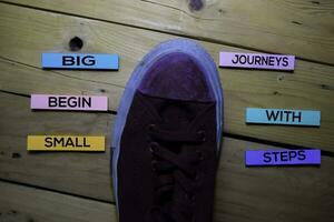 Big Journeys Begin With Small Steps text with sneaker on sticky Notes isolated on table desk background photo