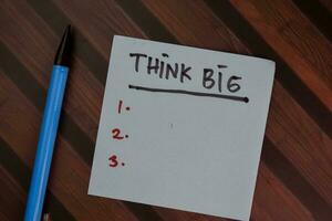 Think Big write on sticky notes and supported by additional services isolated on Wooden Table. photo