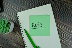 ROIC - Return on Invested Capital write on sticky notes isolated on Wooden Table. photo