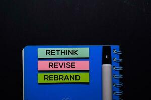 Rethink Revise Rebrand write on Sticky Notes. Top view isolated on black background. photo