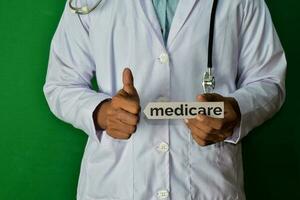 doctor standing on Green background. Hold the Medicare paper text. Medical and healthcare concept. photo