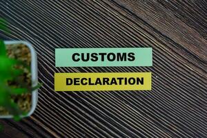 Customs Declaration write on sticky notes isolated on Wooden Table. photo