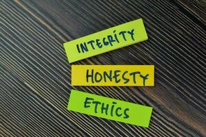 Integrity, Honesty, Ethics write on sticky notes isolated on Wooden Table. photo
