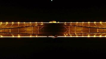 brilhante luzes, pontes com arcos, noite cidade. uma estrada ponte através a rio, ocupado a partir de uma drone. video