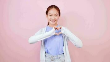 Adorable Asian woman smiling showing heart symbol showing tenderness and love. video