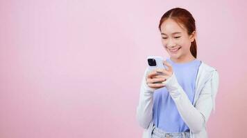 sonriente asiático mujer en casual ropa mirando a teléfono inteligente aplicación utilizando móvil teléfono. video