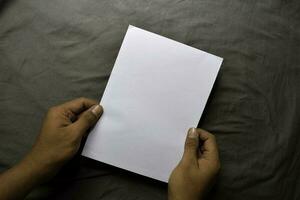 Young man hands holding blank white paper on table background photo