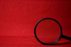 Magnifying glass on red background photo