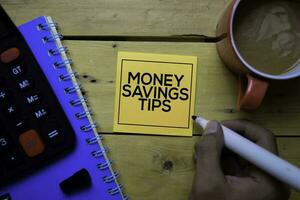 Money Savings Tips write on sticky note with wooden table background photo