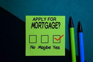 Apply for Mortgage and chec kmark write on a sticky note isolated on Office Desk photo