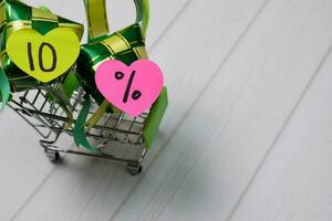 Mini shopping cart and rice dumpling ketupats with 10 percent on sticky note. Ramadan Sale concept photo