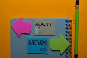 Reality or Expectations write on sticky notes isolated on Office Desk photo