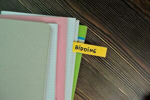 Bidding write on sticky notes isolated on Wooden Table. photo
