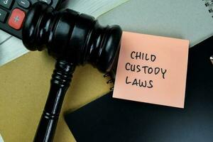 Concept of Child Custody Laws write on sticky notes with gavel isolated on Wooden Table. photo