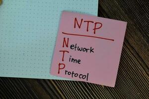 NTP - Network Time Protocol write on sticky notes isolated on Wooden Table. photo