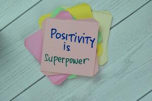 Concept of Positivity is Power write on sticky notes isolated on Wooden Table. photo