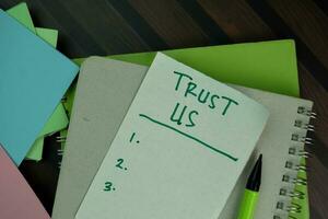 Trust Us write on sticky notes and supported by additional services isolated on Wooden Table. photo